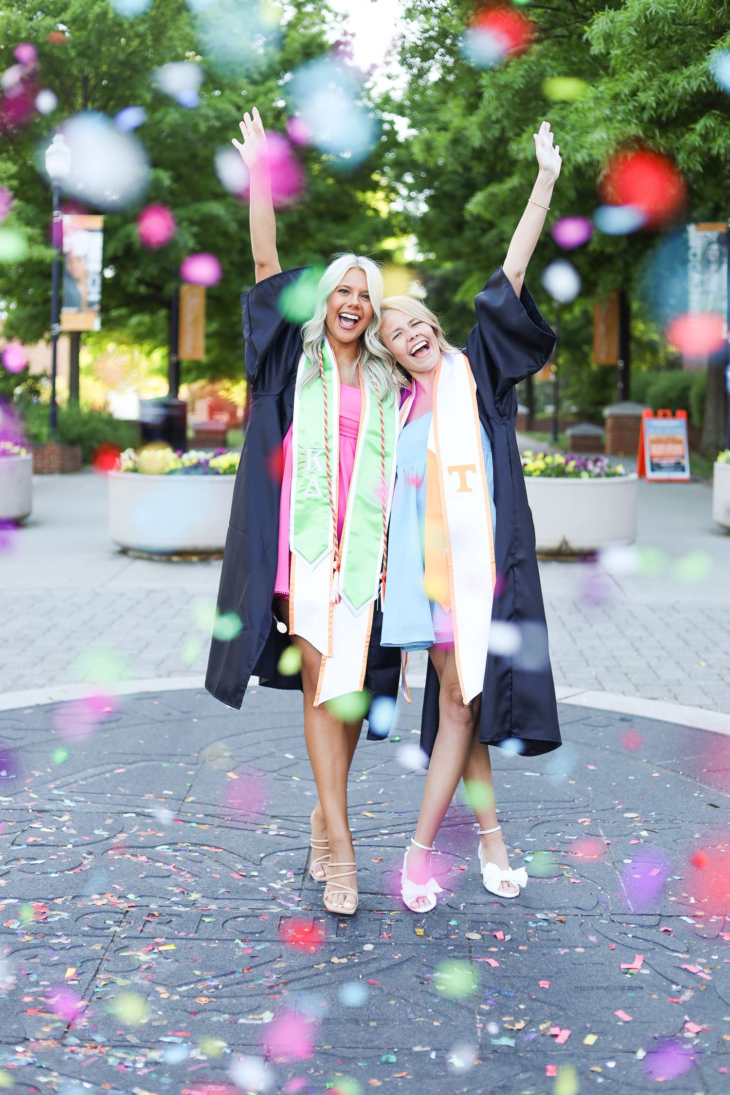 Two girls in front of Ped Walkway at the University of Tennessee. They popped confetti, and they are hugging each other.