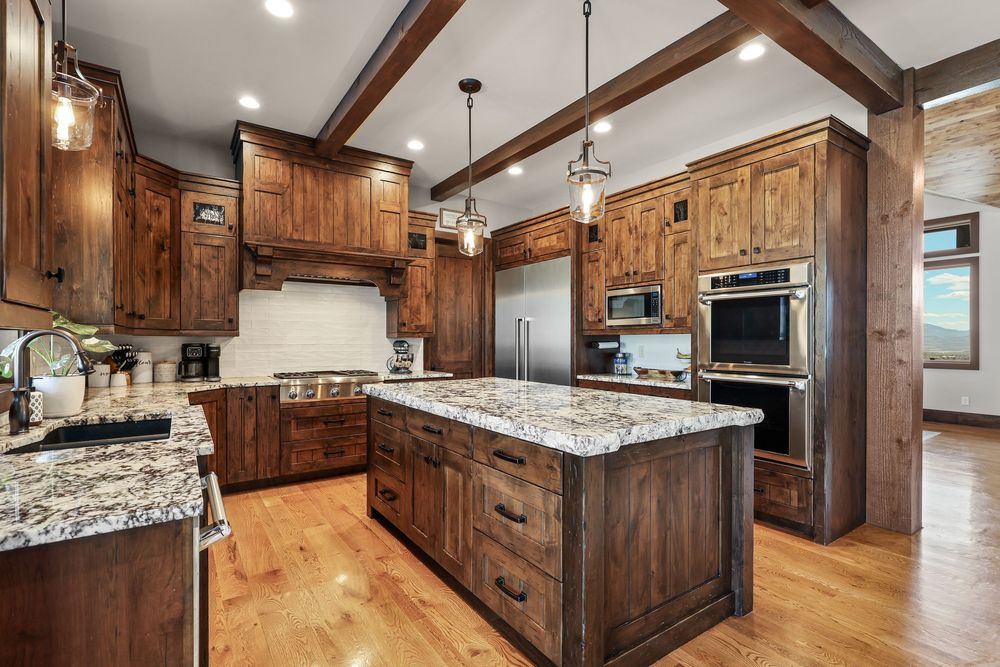 Spacious kitchen with knotty alder cabinets, granite island, stainless appliances, and beam ceiling. Captured by Slate Media (best in UT)