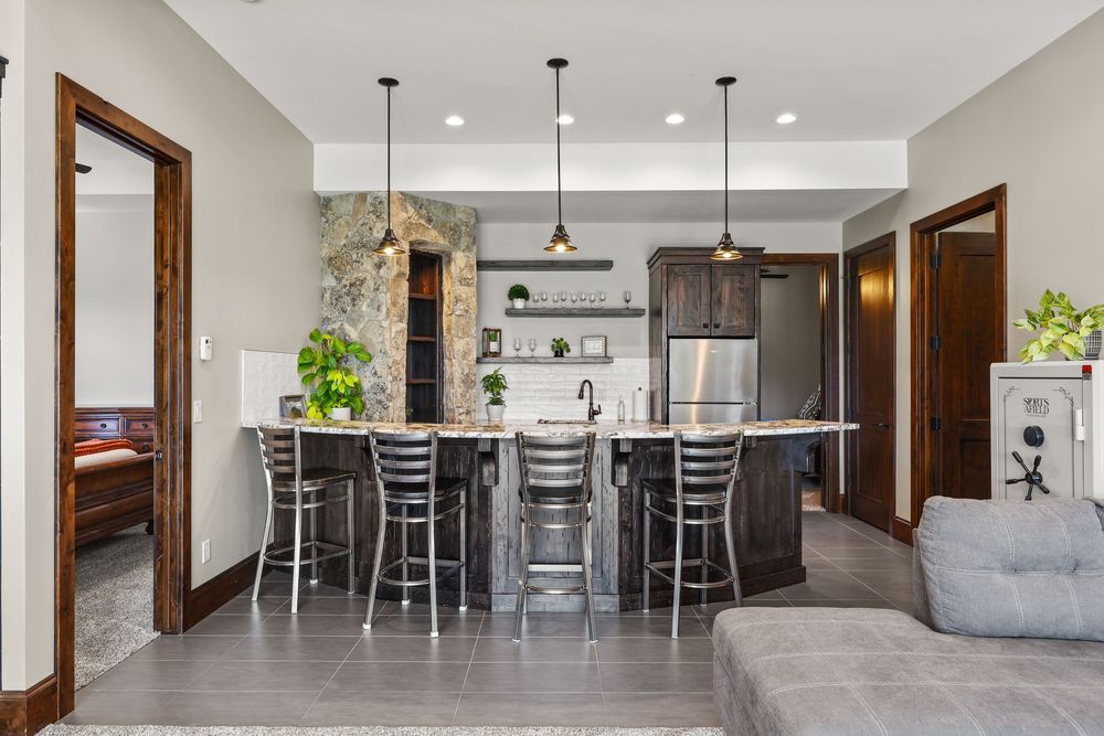Modern kitchen with dark cabinetry, granite island with bar seating, pendant lighting, and stainless steel refrigerator.