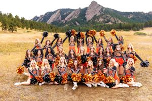 Cheerleading squad posing in uniform with pom-poms against the Flatirons rock formations in Boulder, Colorado.