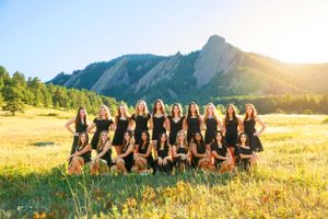 Team photo of cheerleaders in black uniforms against mountain backdrop.
