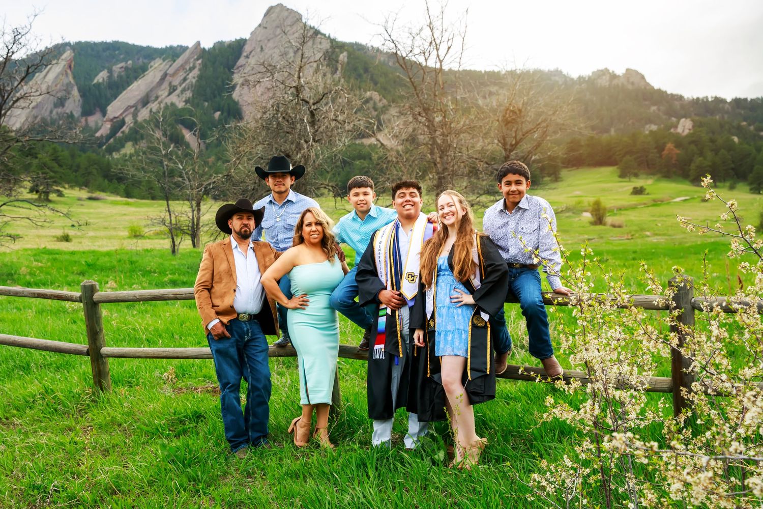 A group of people posing against a scenic mountain backdrop with vibrant green grass and wildflowers in Boulder, Colorado.