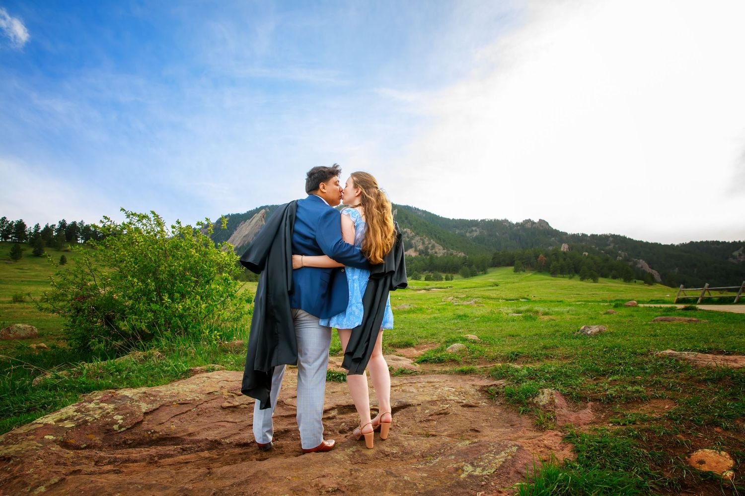 Couple embraces on hilltop overlooking scenic mountain valley during romantic outdoor adventure.