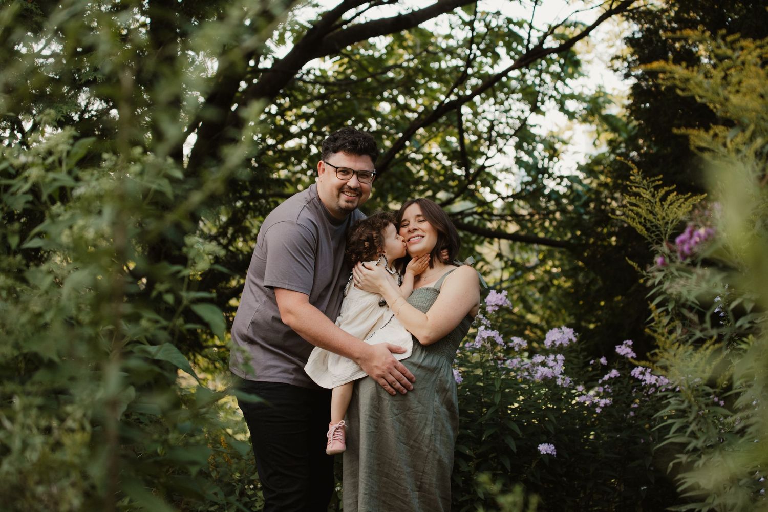 A tender family moment captured in a lush green garden setting.
