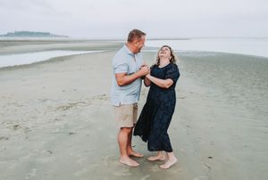 A couple shares an intimate moment during a romantic beach proposal at sunset.
