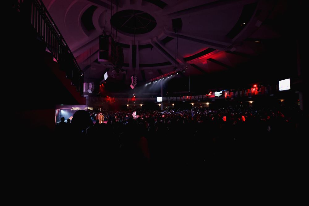 Dark concert venue interior with red ambient lighting and circular ceiling design.