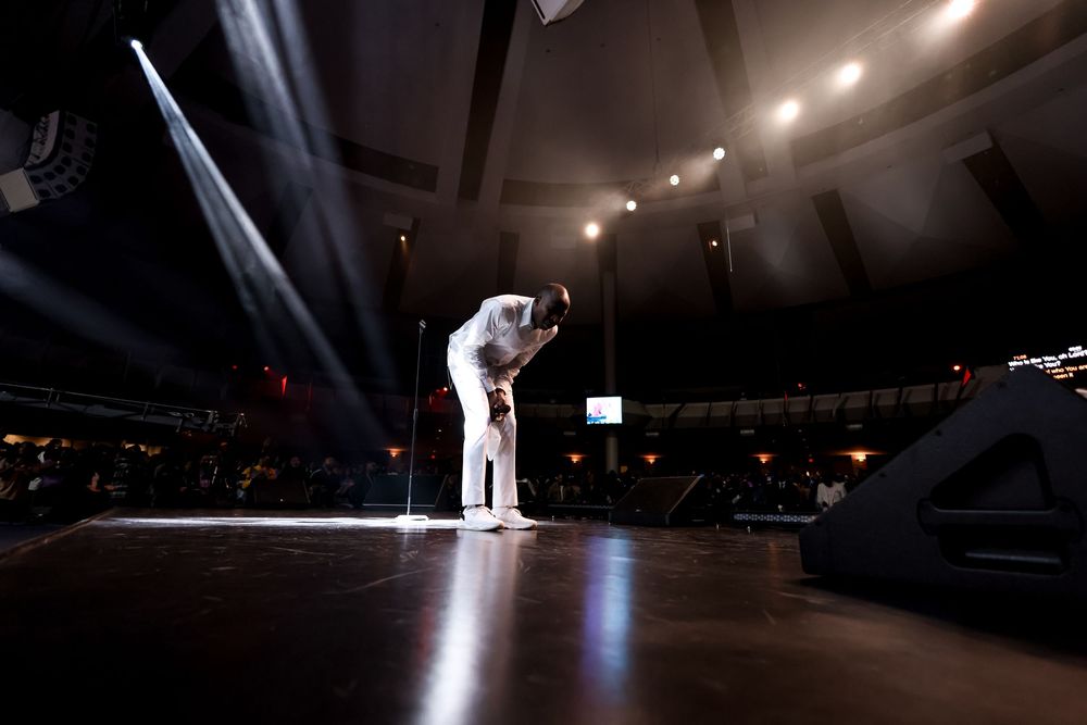 Dramatic low-angle shot of performer in white outfit on illuminated stage.
