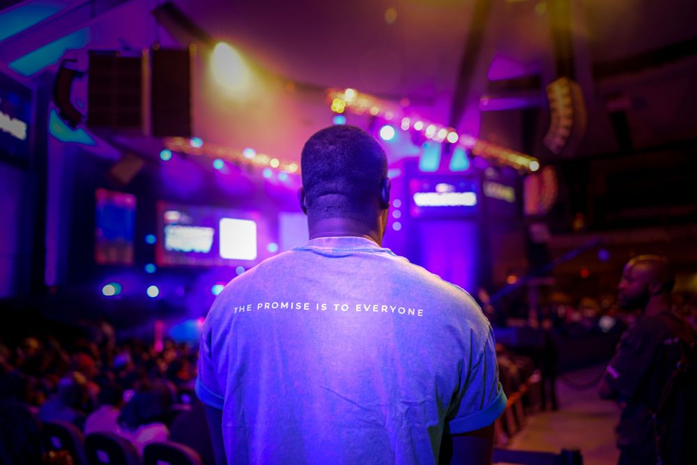 Concert venue with purple lighting and crowd silhouettes creating an atmospheric ambiance.