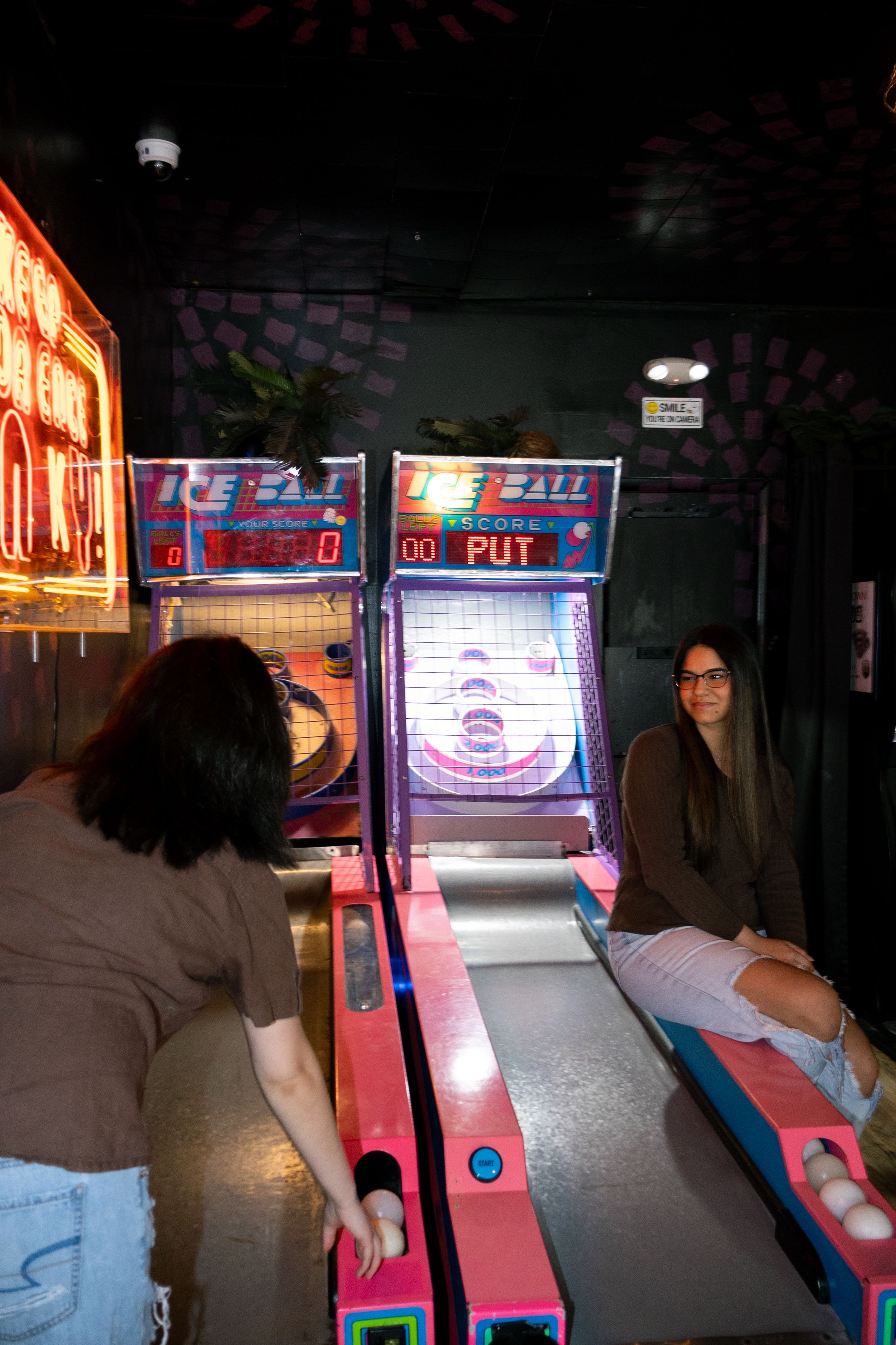 A queer couple plays an arcade game during an anniversary couple session.