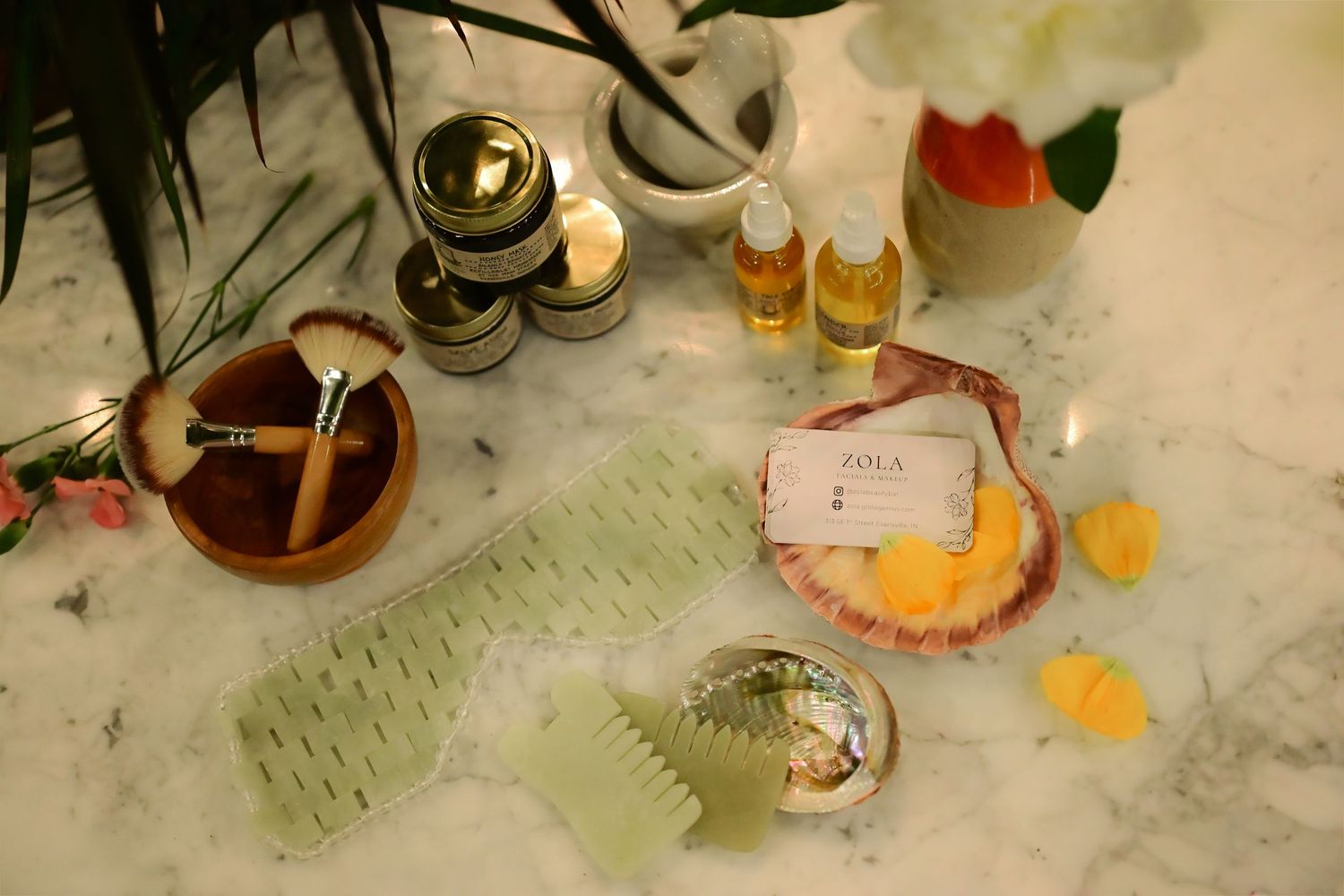 Romantic wedding table setting with peach flowers, wine bottles and white decorative busts.