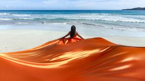 A panoramic view of a sandy beach with rolling waves and turquoise ocean waters stretching to the horizon.