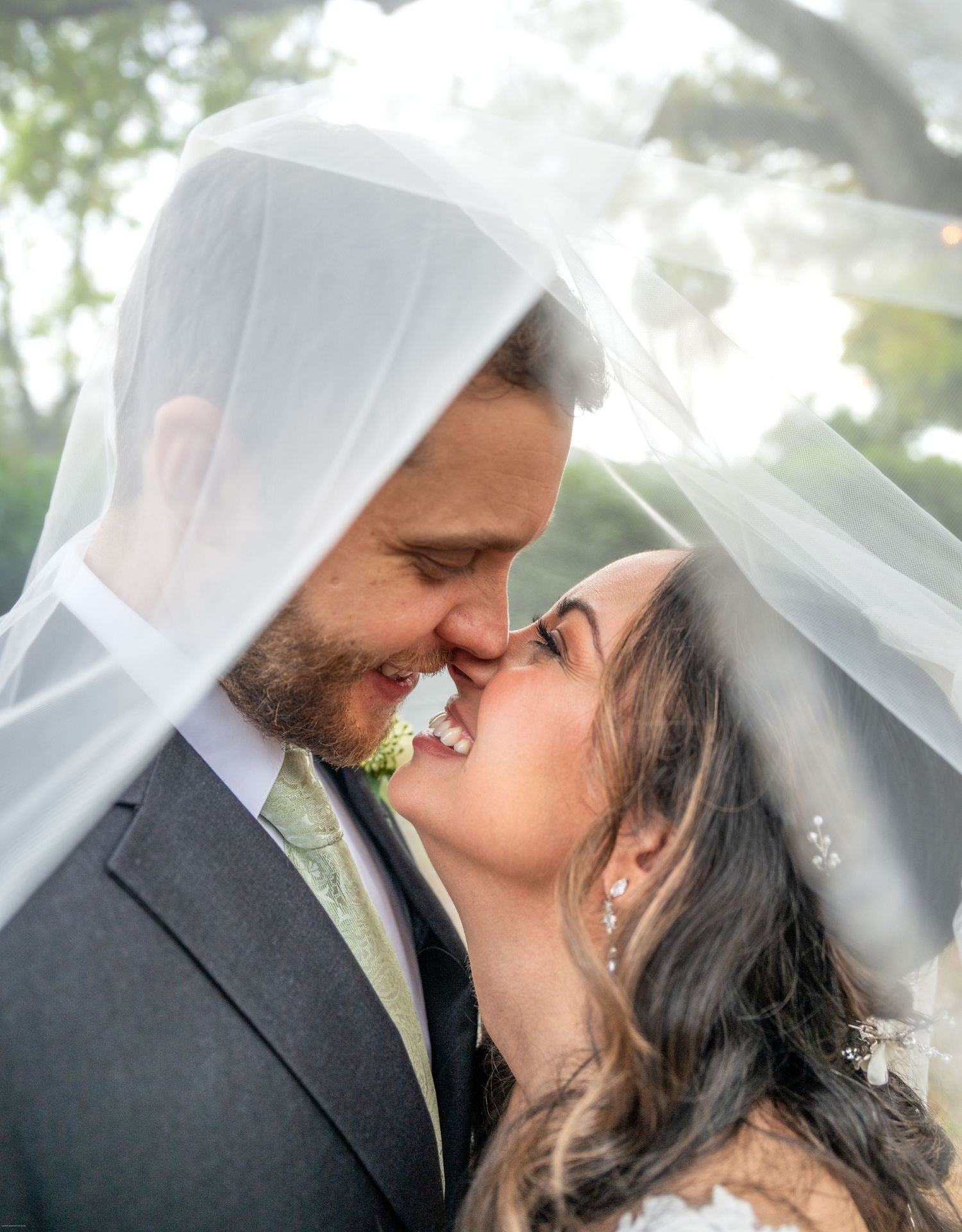 A romantic wedding portrait showcasing a close embrace under a flowing veil.