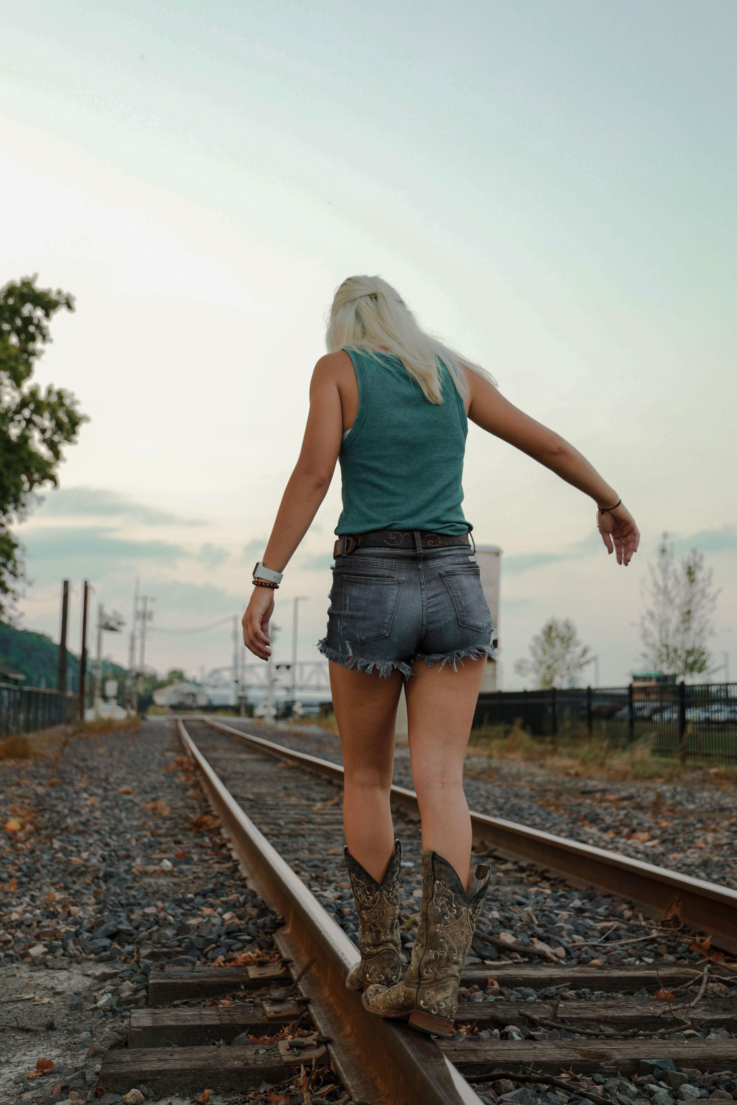 Creative portrait photo of a young woman walking on railroad tracks