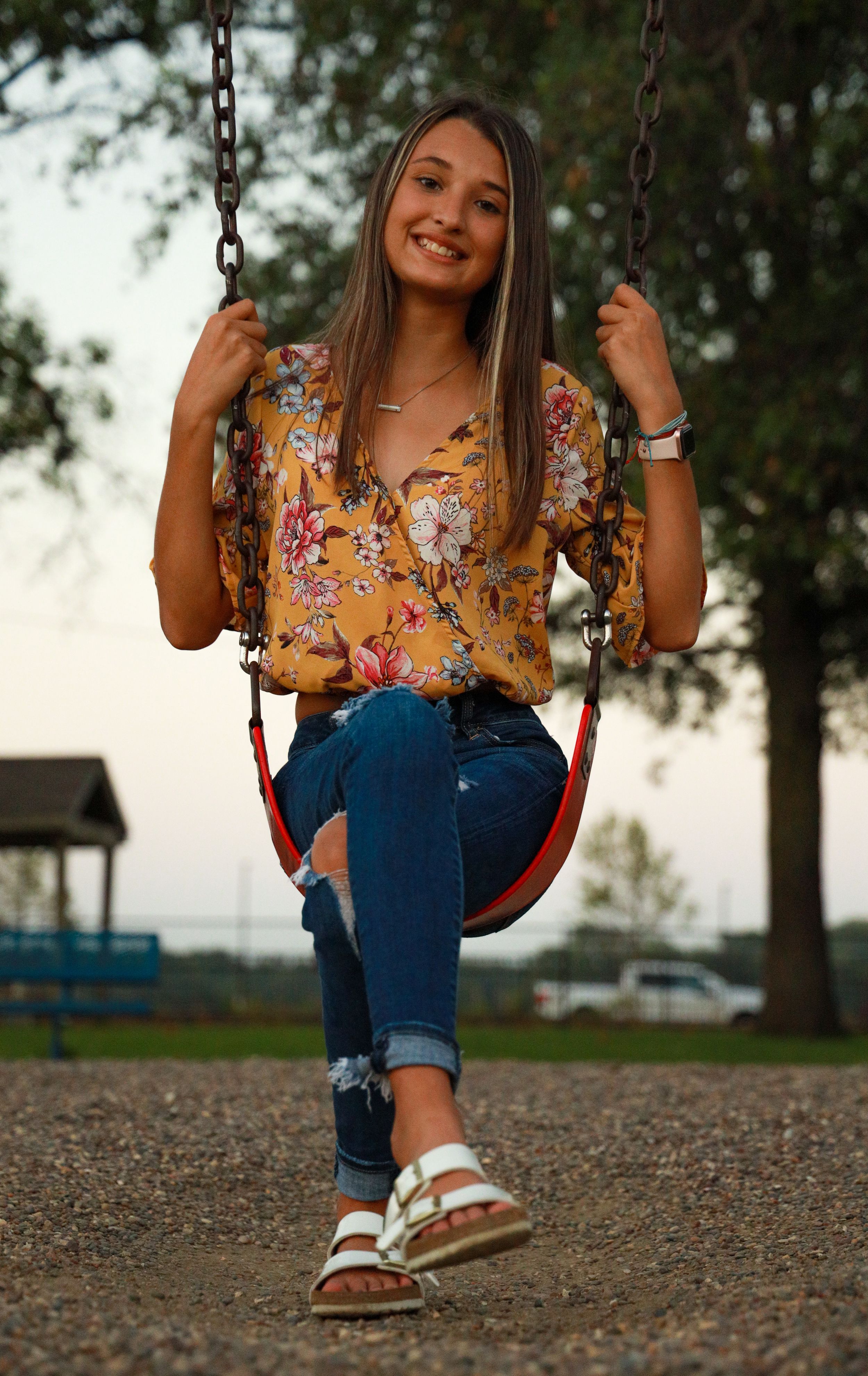 Portrait photo of a teen girl sitting in a playground swing