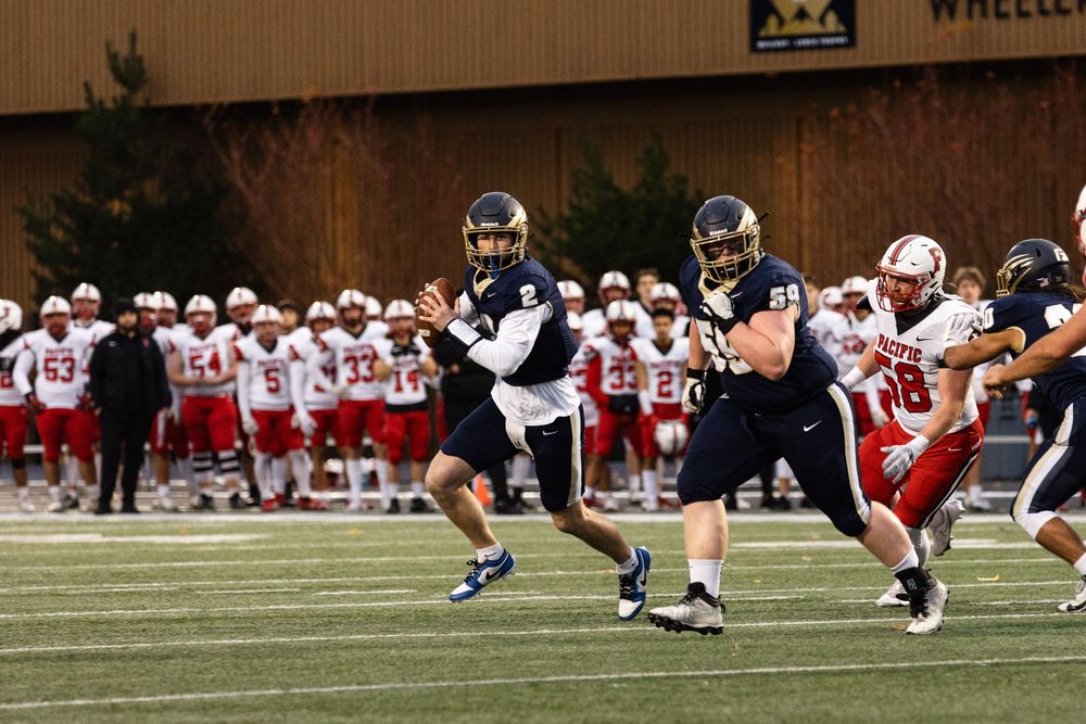 Football players in navy and red uniforms competing during a nighttime game at George Fox University.