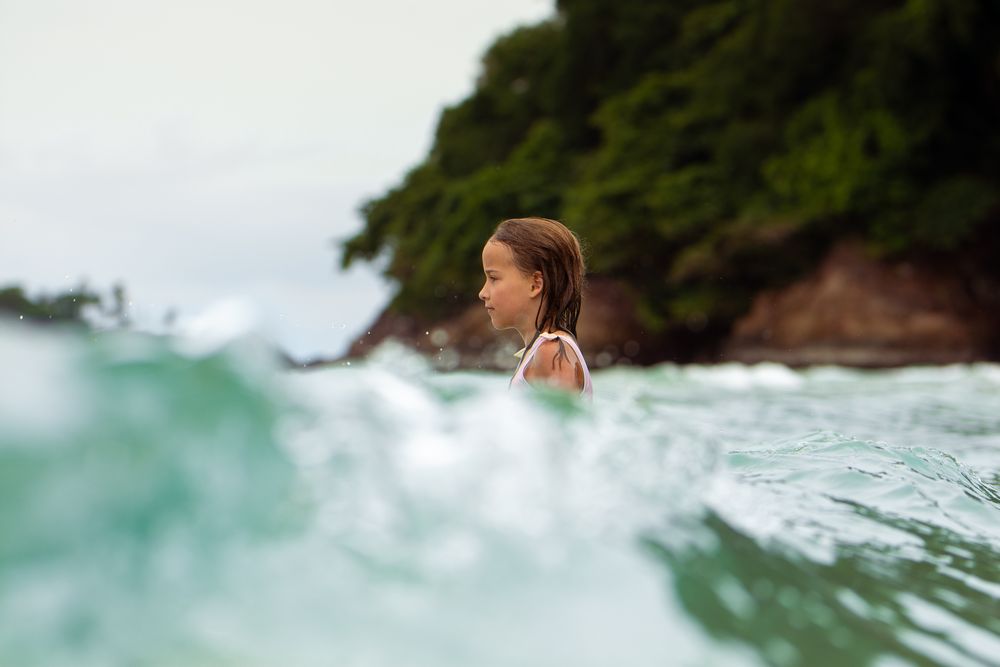 A little girl is swimming in the waves in turquoise ocean waters in Thailand, Koh Chang