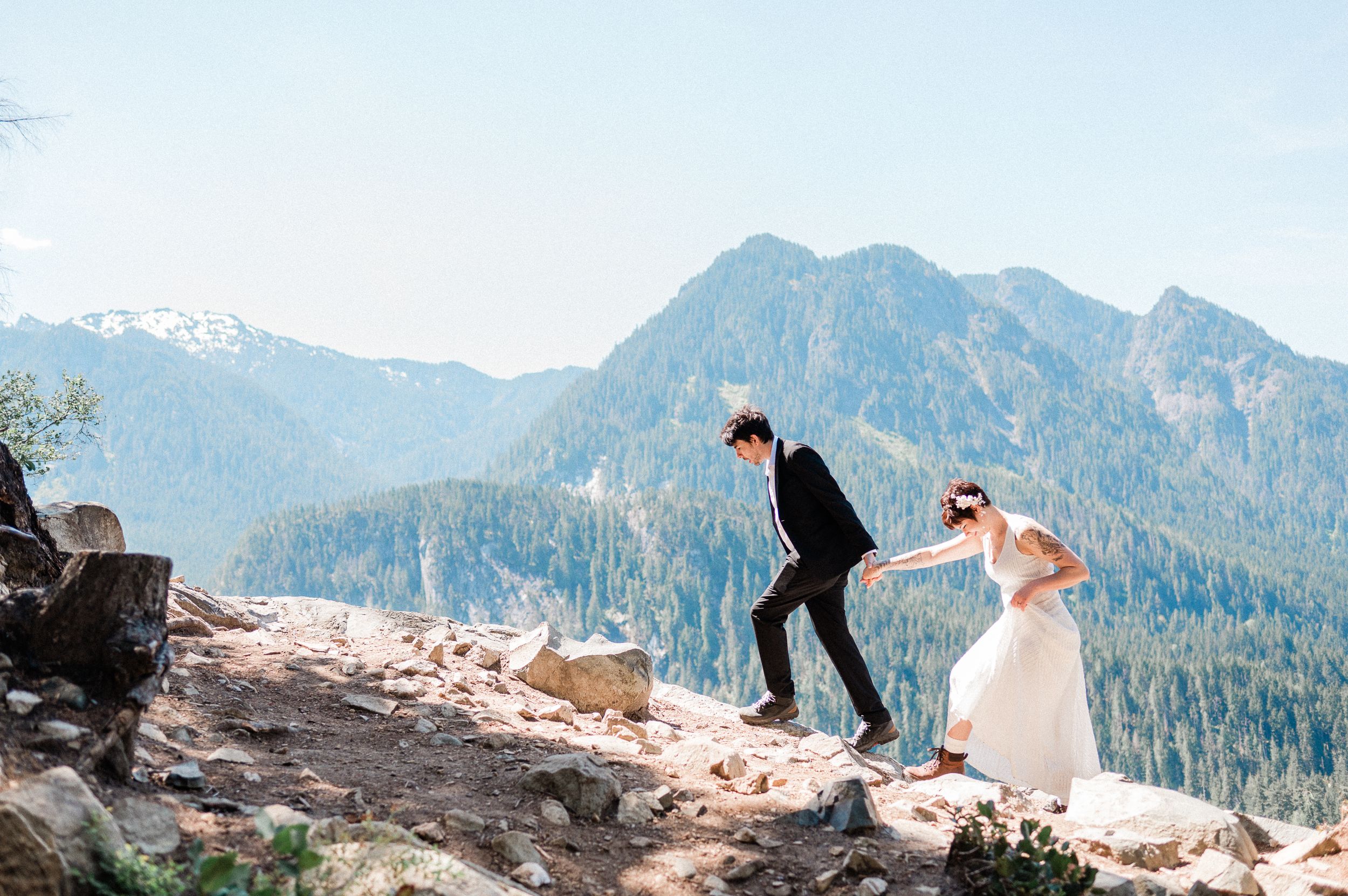 groom leading bride up a mountain during their Washington elopement.