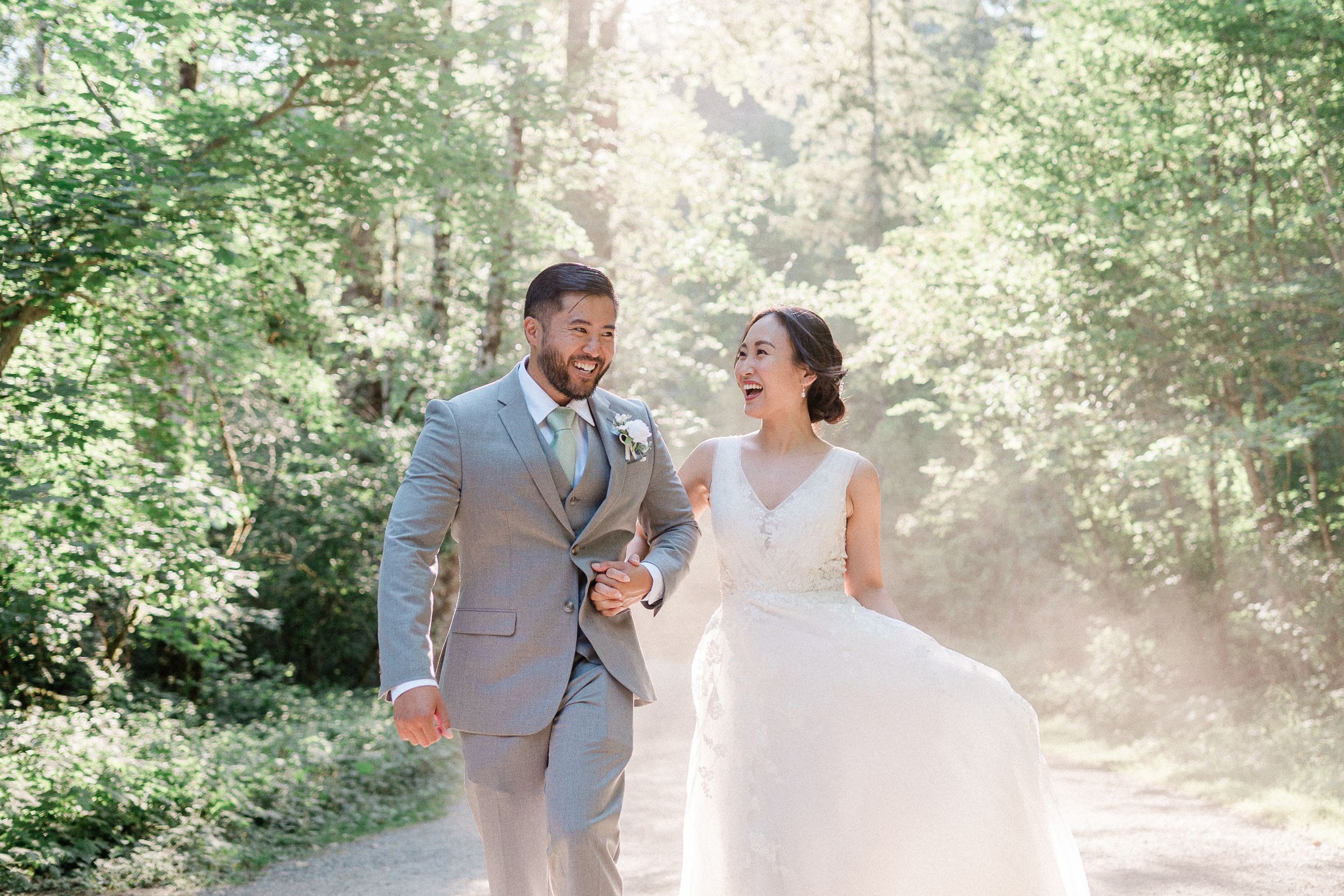 bride and groom laughing walking on dusty forest road during their Rattlesnake Lake elopement.