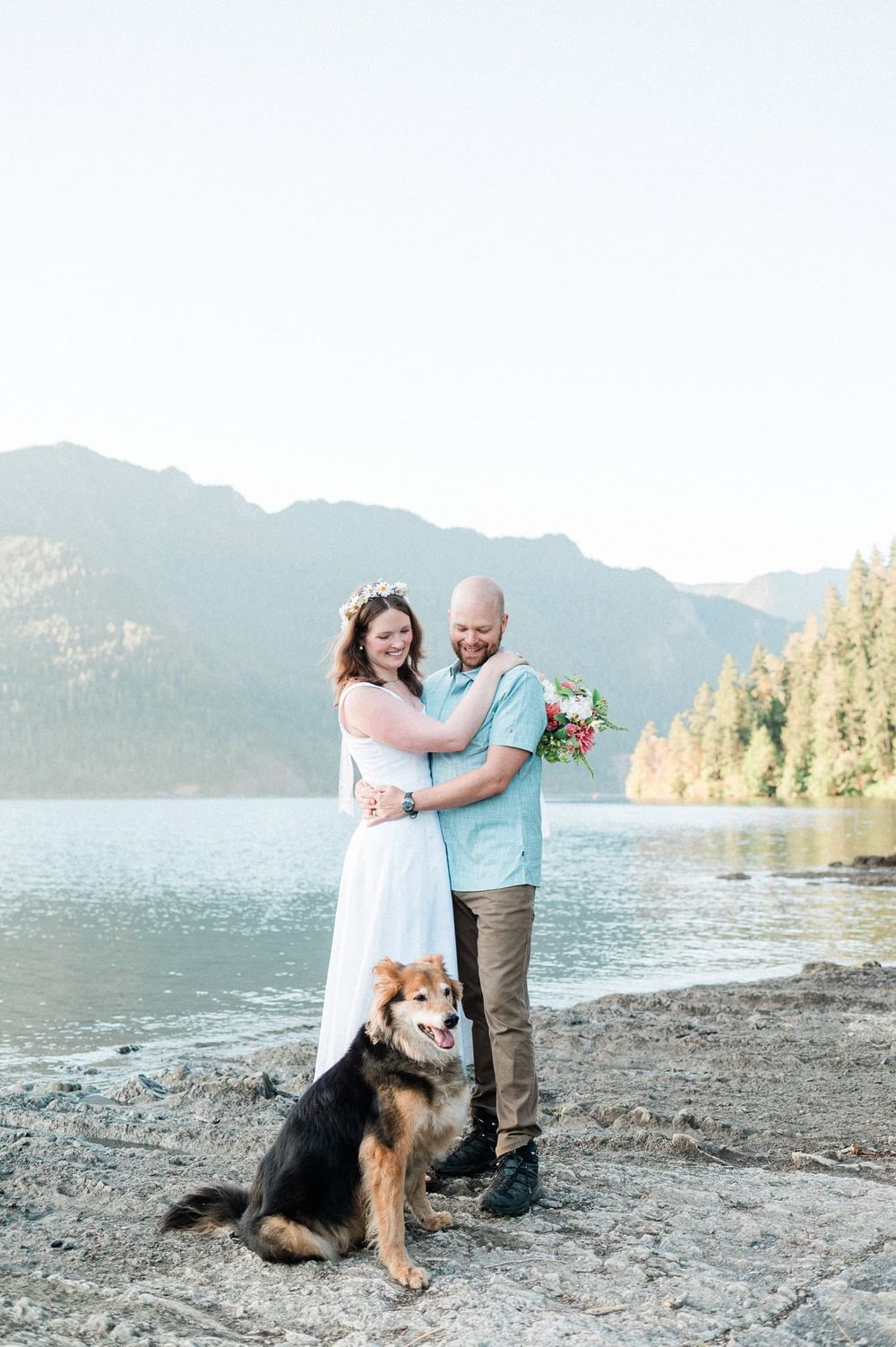bride and groom with dog near lake and mountains