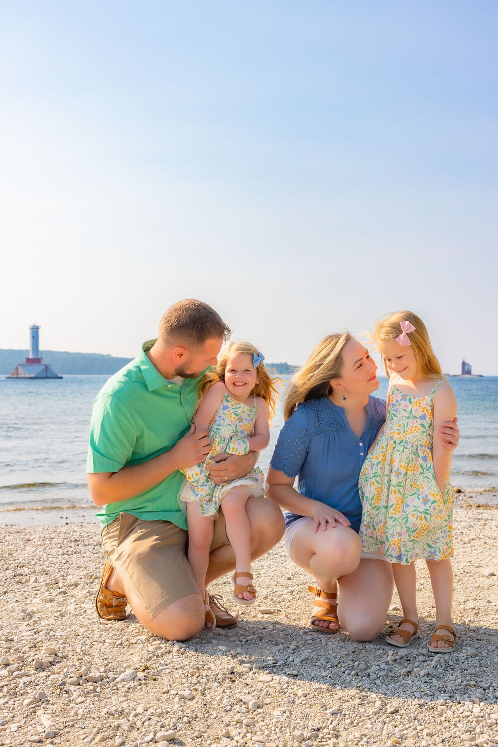 Family in coordinating blue and green outfits sharing joyful moments together on a sunny beach.