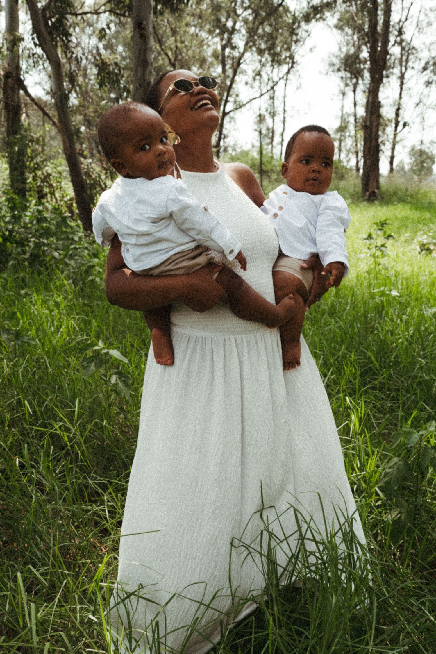 Family group wearing matching white outfits poses in grassy outdoor setting.