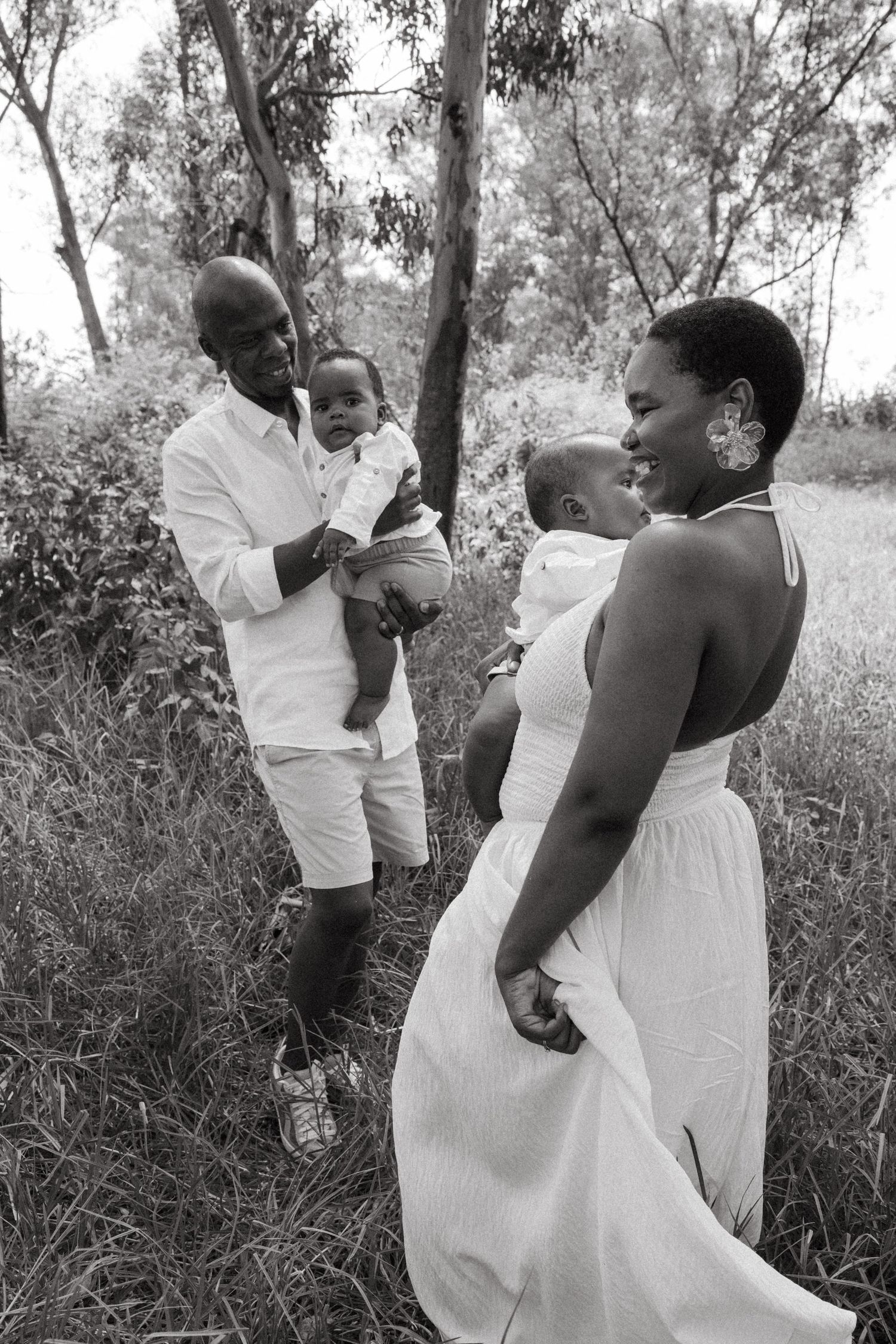 Black and white photo of family members embracing and laughing together outdoors.