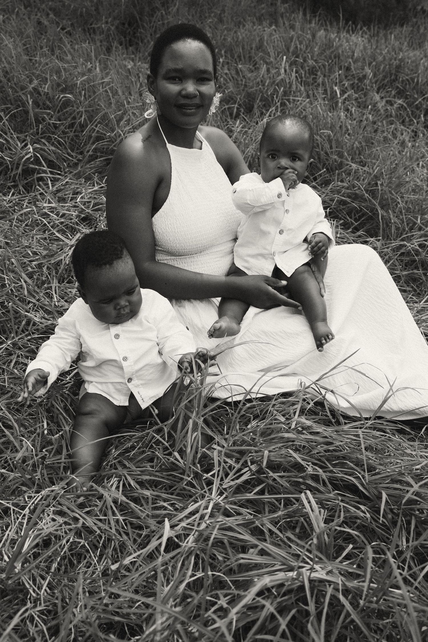Black and white portrait of a family sitting together in tall grass.