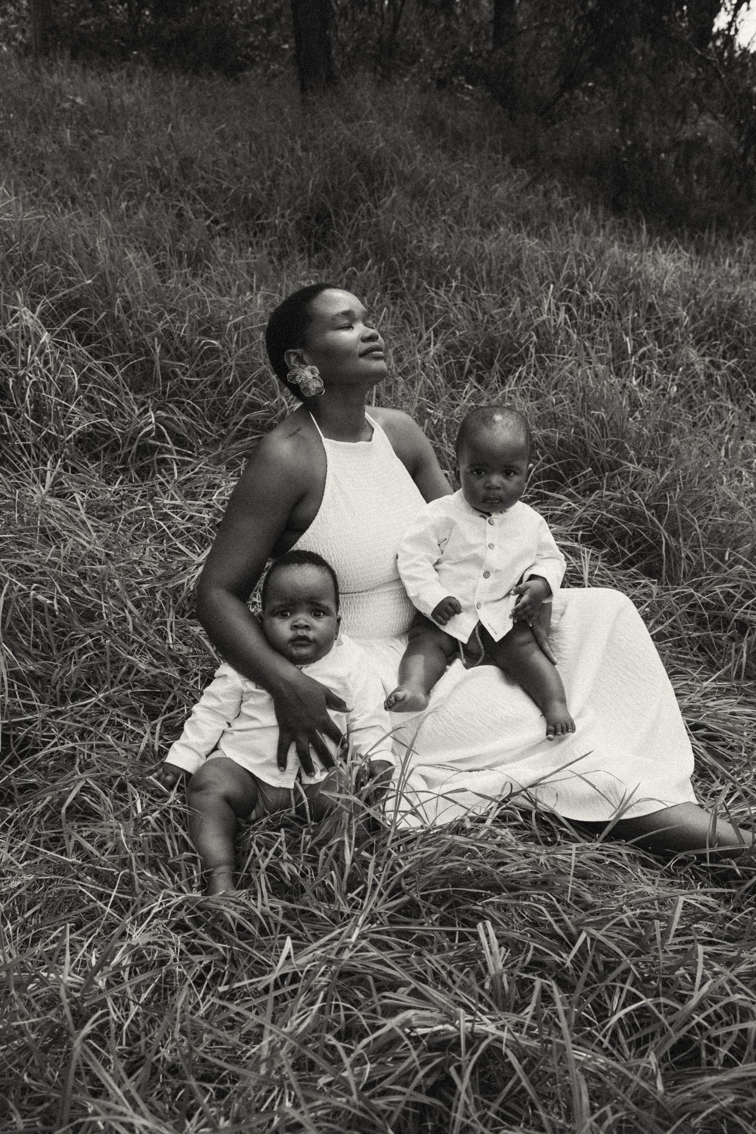 Candid black and white photo of a family relaxing in a grassy field.