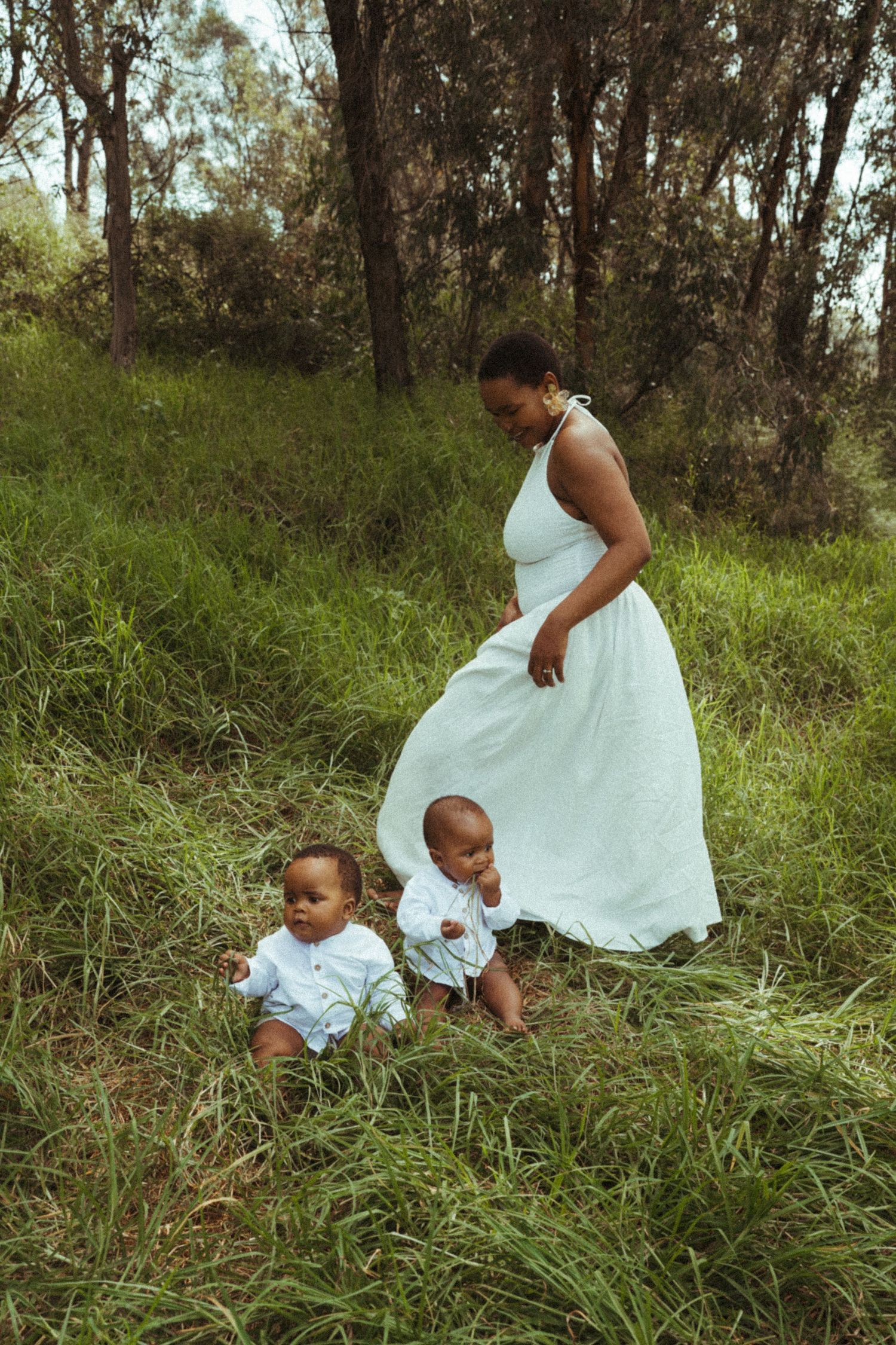 Family in white outfits playing together in grassy field.