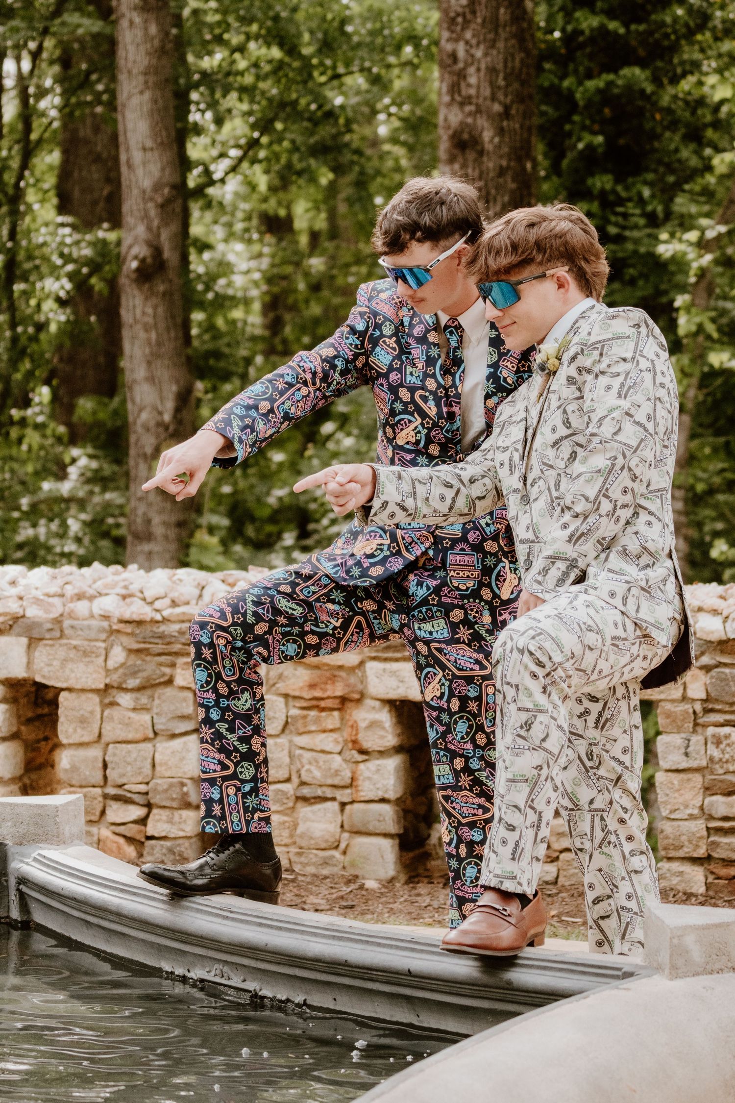 Two people in patterned pajamas sitting on stone wall by water.