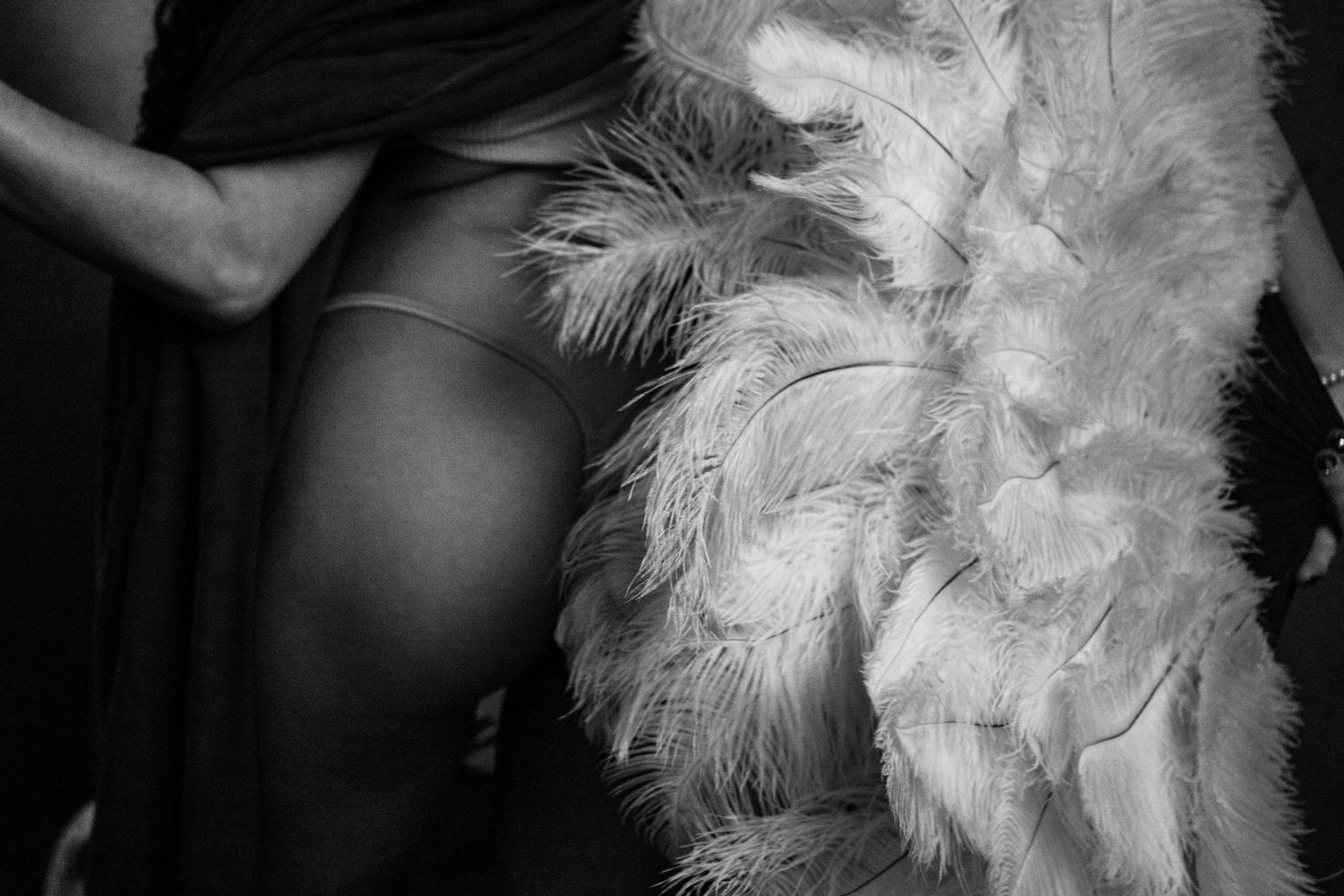 Romantic monochrome boudoir photograph close up of a showgirl with feather fan