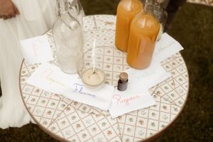 Paper notes and orange juice bottles arranged on a patterned white tablecloth with decorative geometric designs.