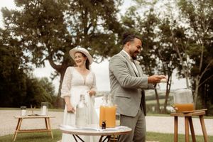 Couple serving drinks at outdoor summer wedding with rustic beverage stations and refreshments.