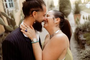 A couple shares an intimate laughing moment against a backdrop of desert plants and cacti.