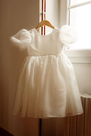 Soft white chiffon tulle fabric drapes elegantly over a dress form in natural sunlight through a window.