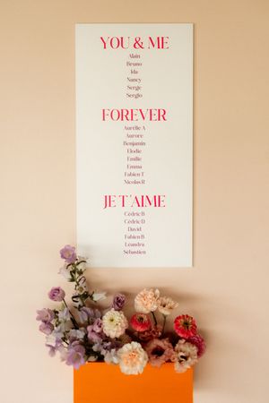 A romantic sign with 'You & Me Forever Je t'aime' text displayed above an orange box filled with pink and purple flowers.