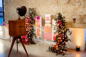 Vintage camera setup with floral arrangements and signage in an event space with exposed stone walls.