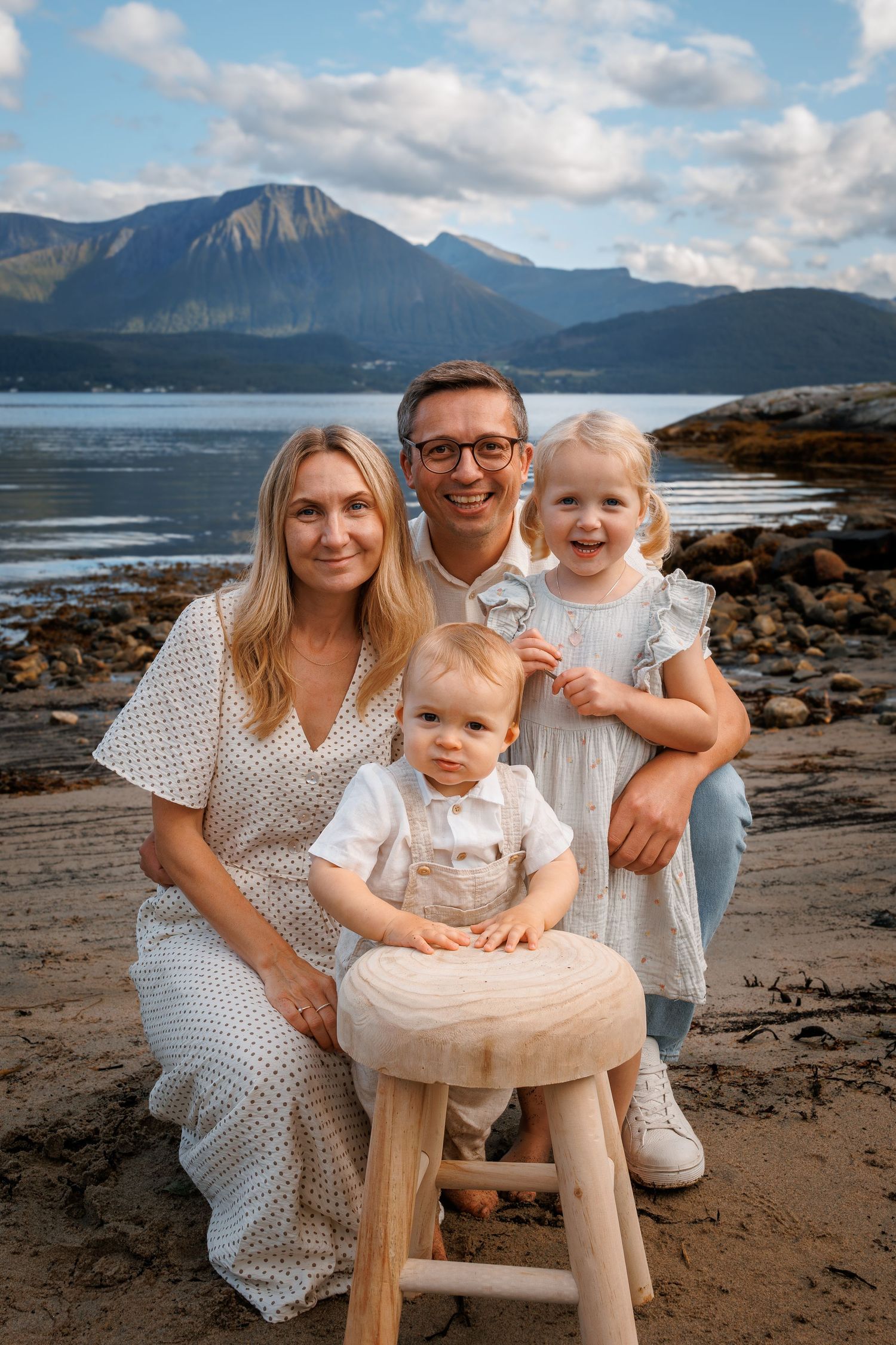 A family poses on a rocky beach with mountains and water in the backdrop near Oahu's north shore.