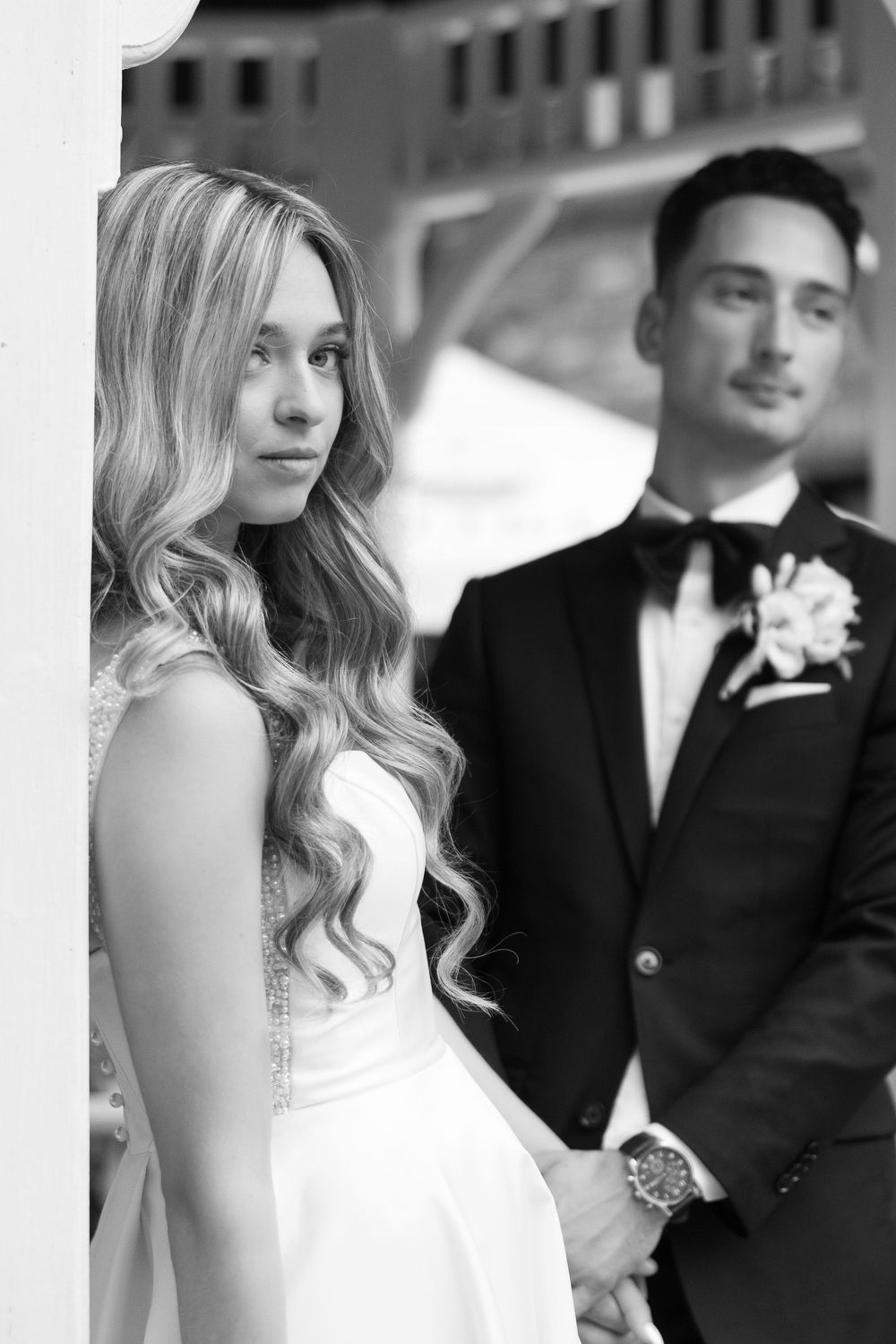 Black and white wedding photos showing romantic moments between bride in white dress and groom in dark suit.