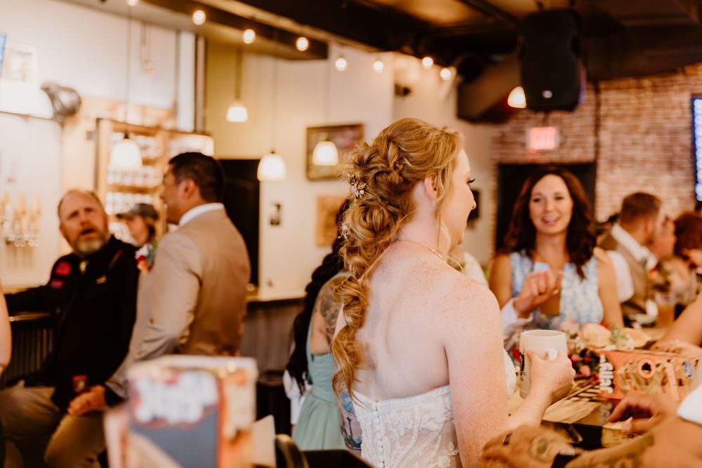 Reception scene with decorative lighting and exposed brick walls as guests mingle in the background.