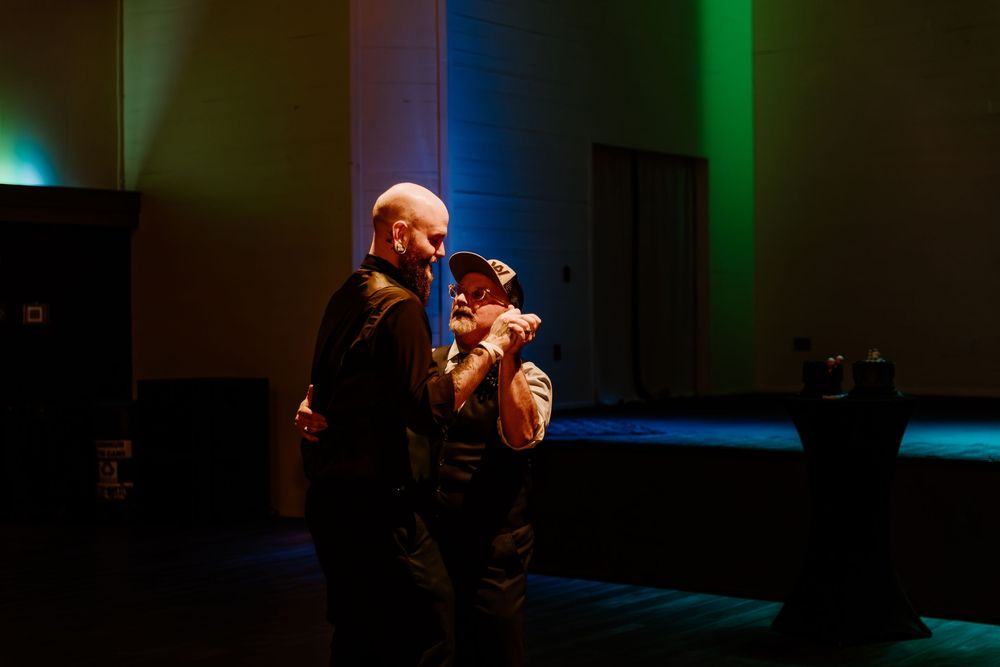 A dark theater stage illuminated with green and blue lighting creates a moody atmospheric scene.