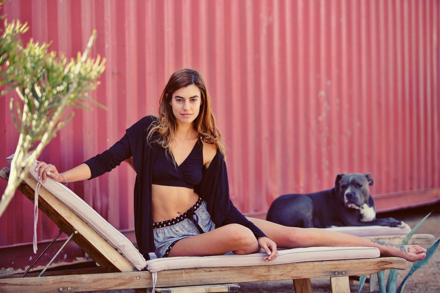 Woman leaning against blue wall wearing a navy geometric honeycomb patterned vest top.