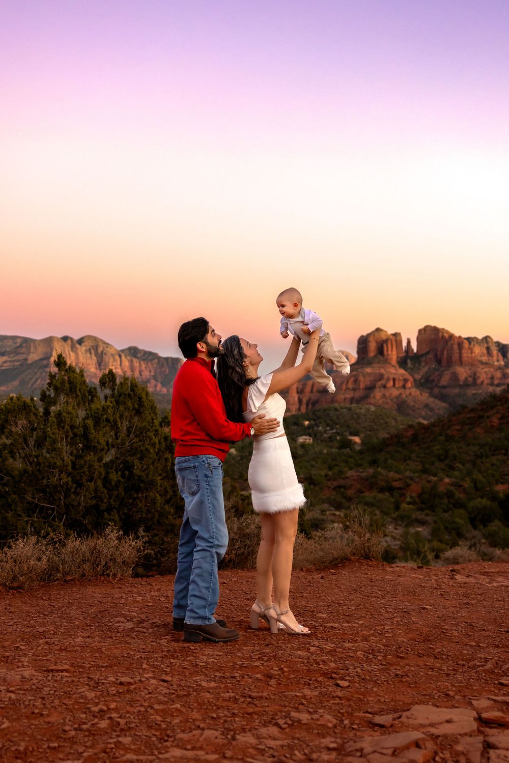 Family shares a tender sunset moment against the stunning red rock formations of Sedona, Arizona at dusk. Sedona Family Portrait Photography