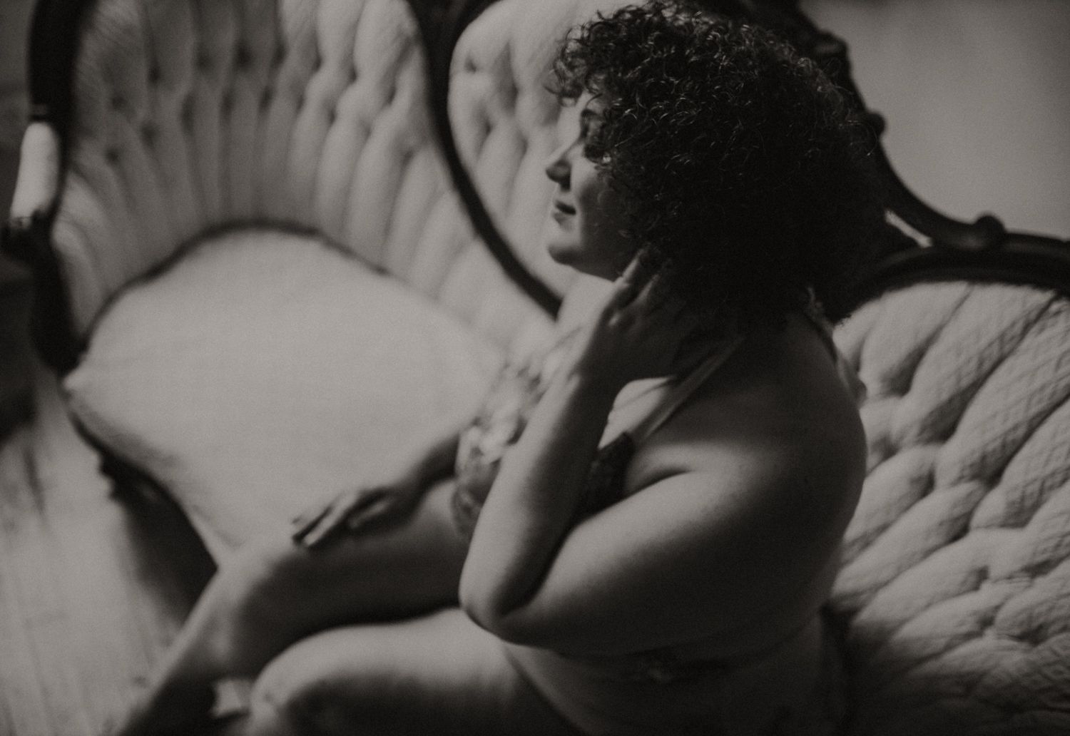 Black and white boudoir portrait on vintage tufted furniture.