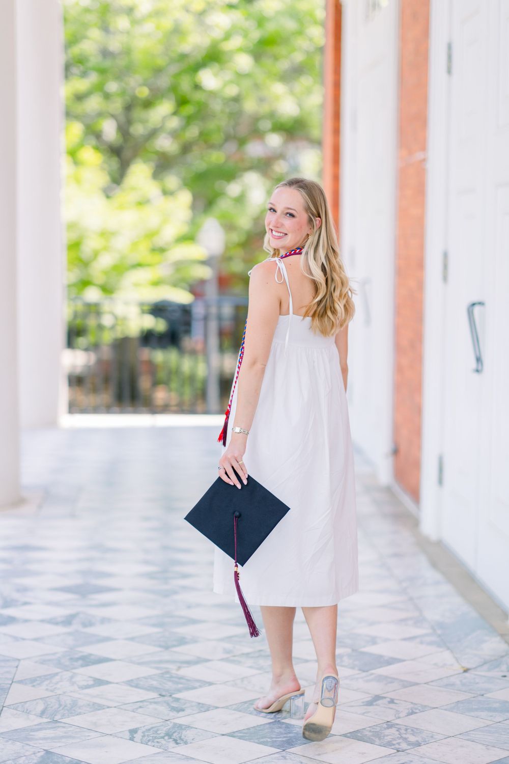 Graduation photos taken under white columned walkway with brick accents.
