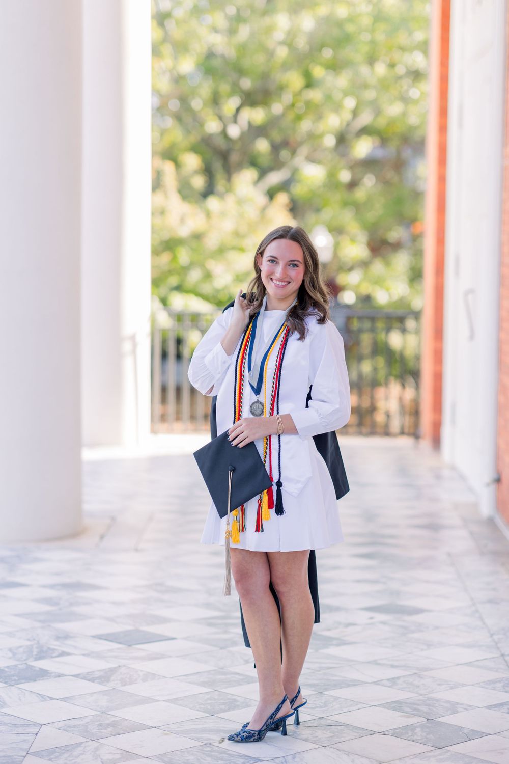 Professional photoshoot in a white columned walkway featuring formal attire and accessories.