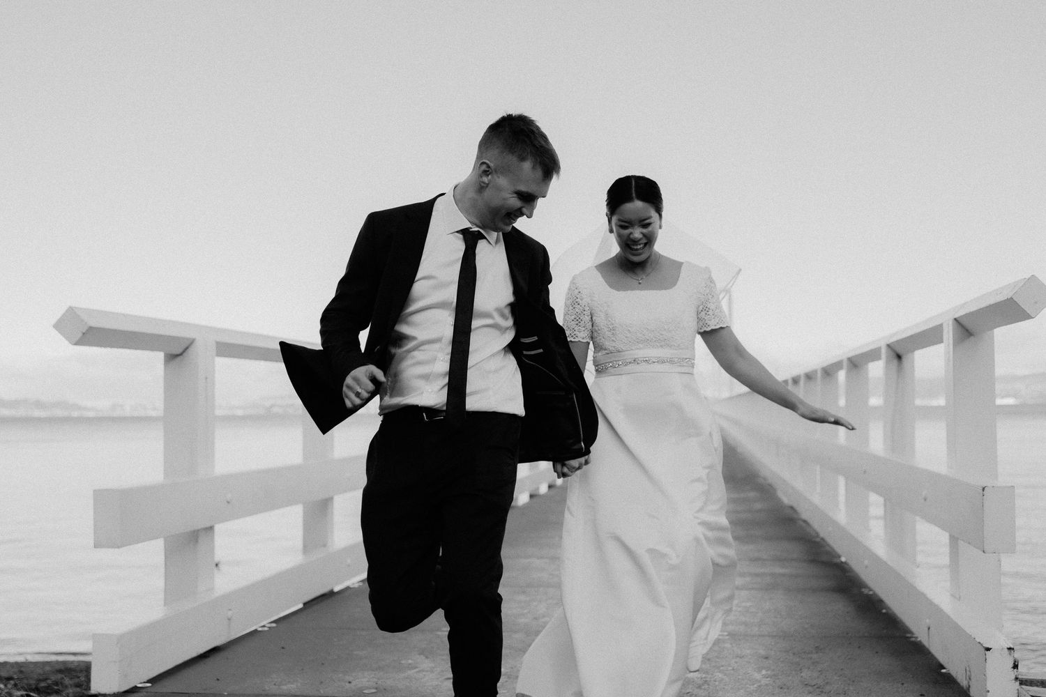 bride and groom walk through the fields of long grass at sunset