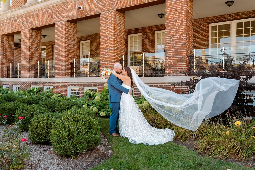 A bride and groom share a romantic moment together in front of a brick building with white columns.