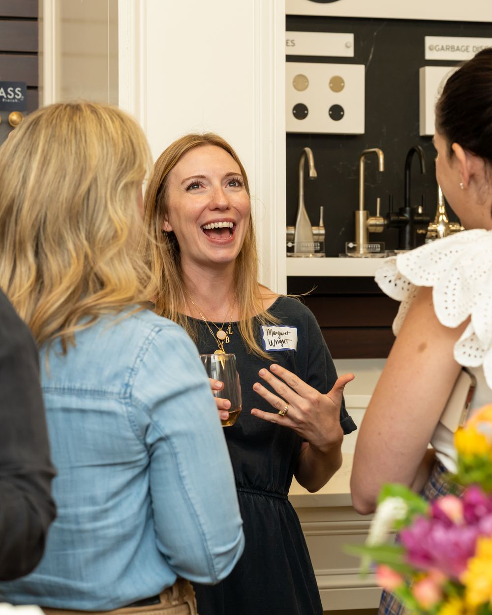 People mingling and socializing at a casual business event in a kitchen setting.