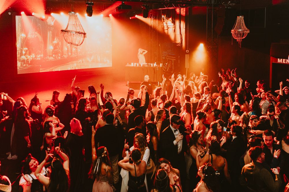 Energetic crowd at nightclub event with red lighting and atmospheric effects.